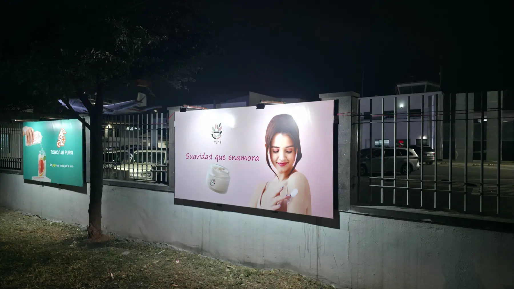 Dos anuncios iluminados sobre la barda exterior del aeropuerto ADN